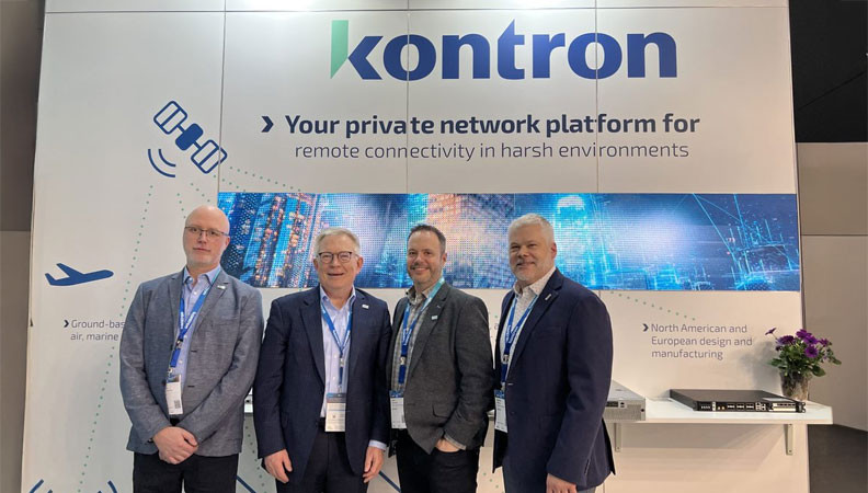 Four men stand together at a conference booth for Kontron, which showcases their private network platform for remote connectivity in harsh environments. The backdrop features graphics highlighting technology and connectivity solutions.