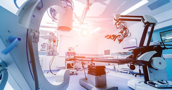 A modern surgical room featuring advanced robotic surgical equipment, bright lighting, and various medical machines. The room is clean and designed for high-tech medical procedures.