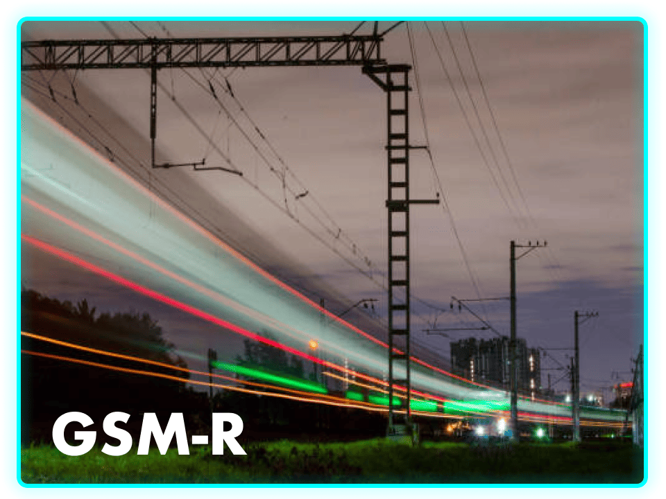 A nighttime scene featuring railway tracks with dynamic light trails from a passing train. Overhead, power lines and poles are silhouetted against a cloudy sky. The text "GSM-R" is displayed in a bold font at the bottom left.