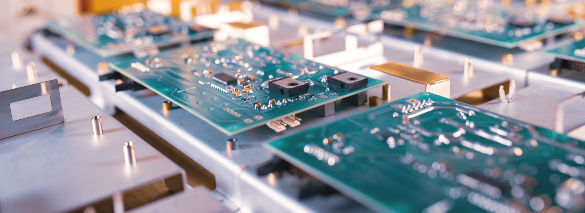 Close-up of multiple green circuit boards arranged on a metallic surface, showcasing intricate electronic components and connections.