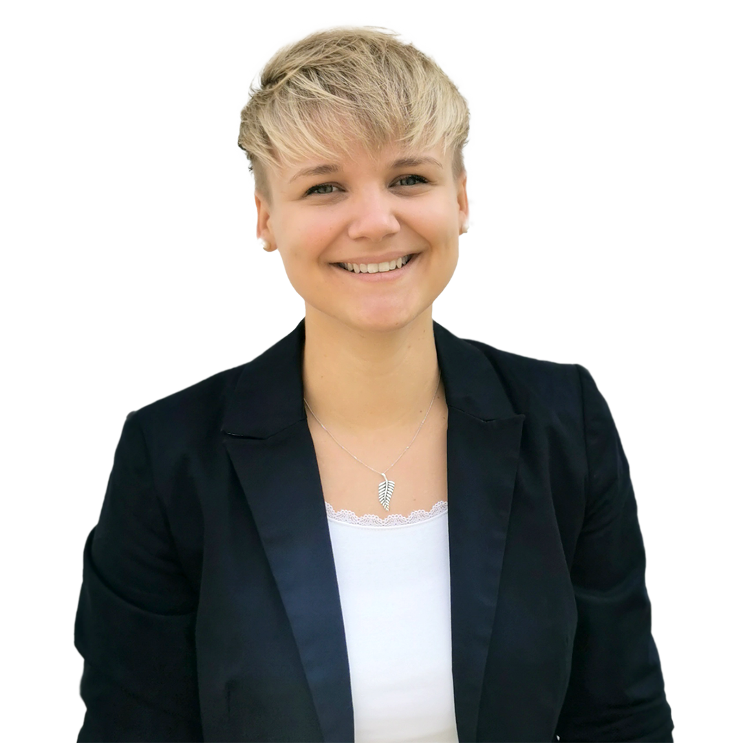 Smiling young woman with short blonde hair, wearing a black blazer over a white top, standing against a plain white background.