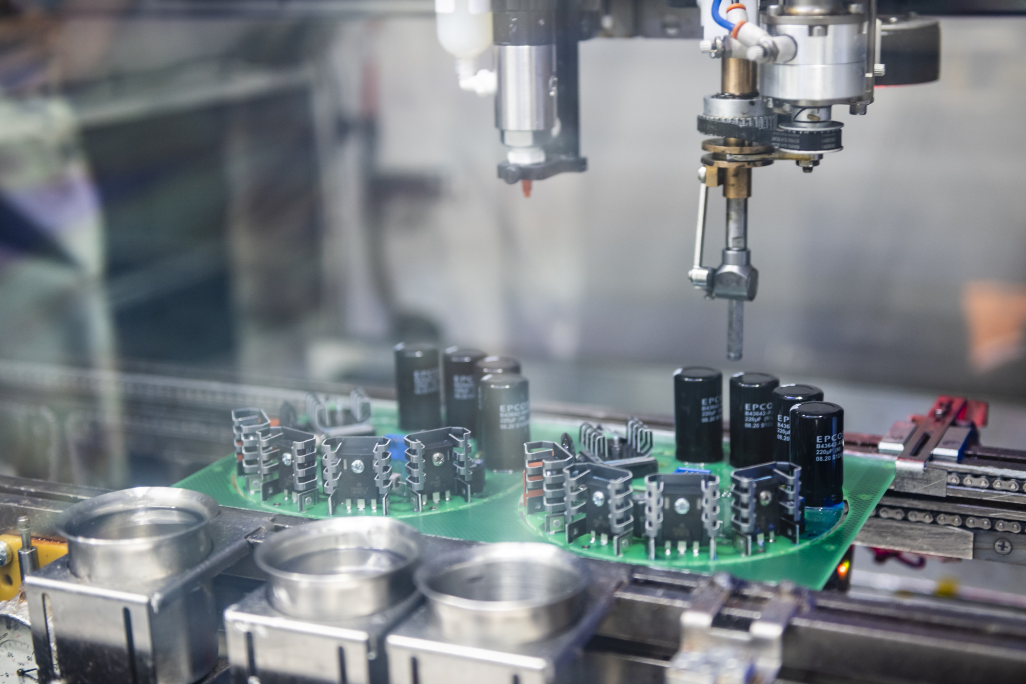 A robotic arm assembling electronic components on a printed circuit board in a manufacturing facility.