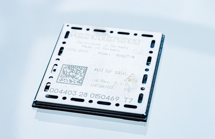Ein silberner Mikrochip mit der Aufschrift "Kontron" und verschiedenen technischen Informationen. Der Chip ist quadratisch und hat eine glatte, reflektierende Oberfläche.
