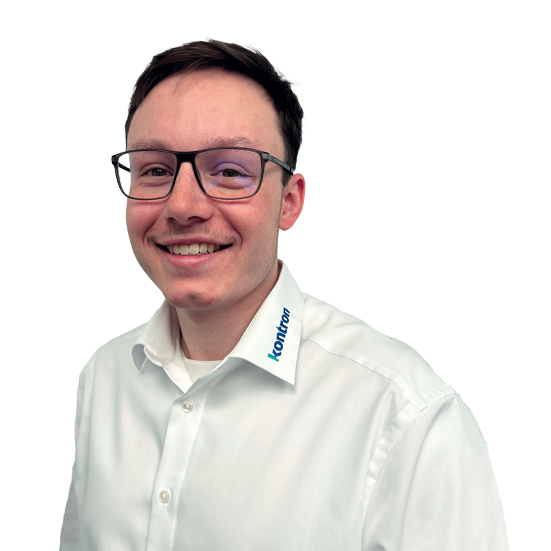 A young man with short brown hair and glasses smiles while wearing a white collared shirt with the word "Kontriar" embroidered on the collar. The background is plain white.