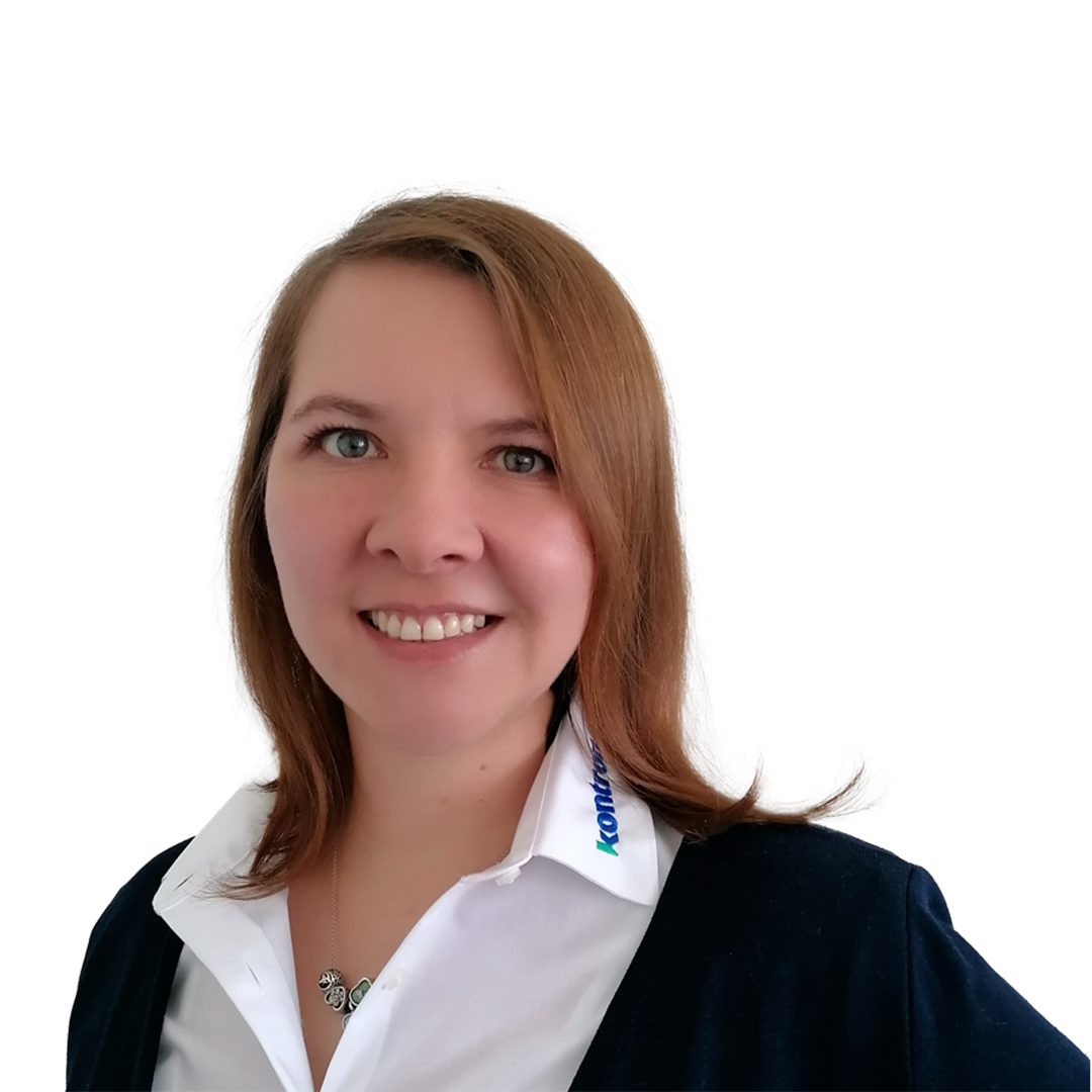 A woman with shoulder-length brown hair smiles at the camera. She wears a white collared shirt with a dark sweater over it, and a pendant necklace. The background is plain white.