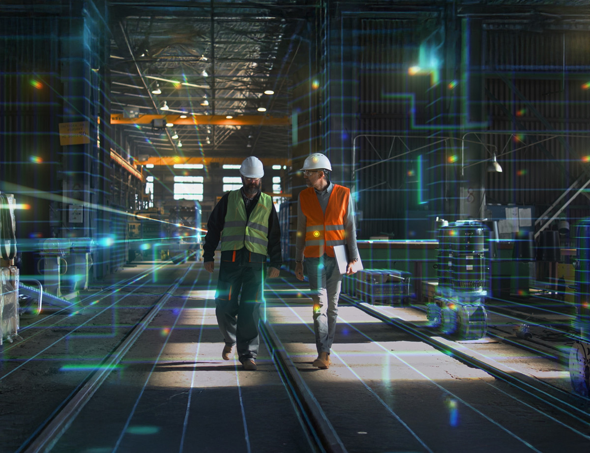 Zwei Bauarbeiter in Sicherheitswesten und Helmen gehen durch eine Industriehalle. Digitale Grafiken scheinen den Raum zu durchziehen, was ein Gefühl von technologischem Fortschritt vermittelt.